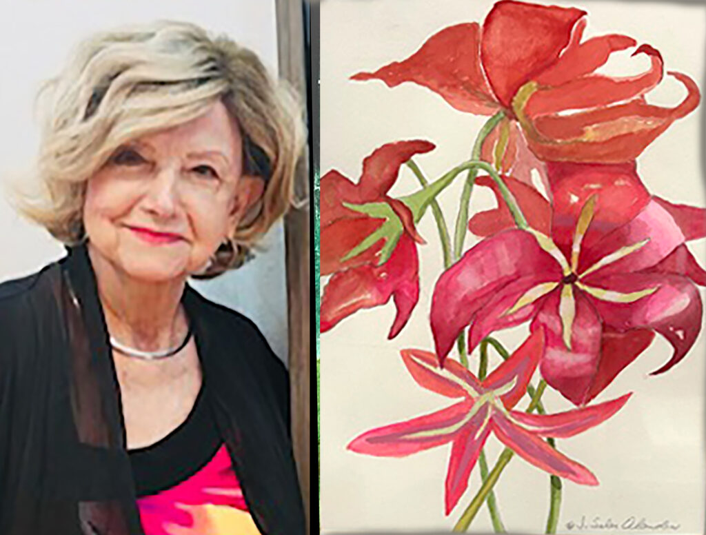 A woman poses next to a painting of bright red lilies painted on a canvas. 