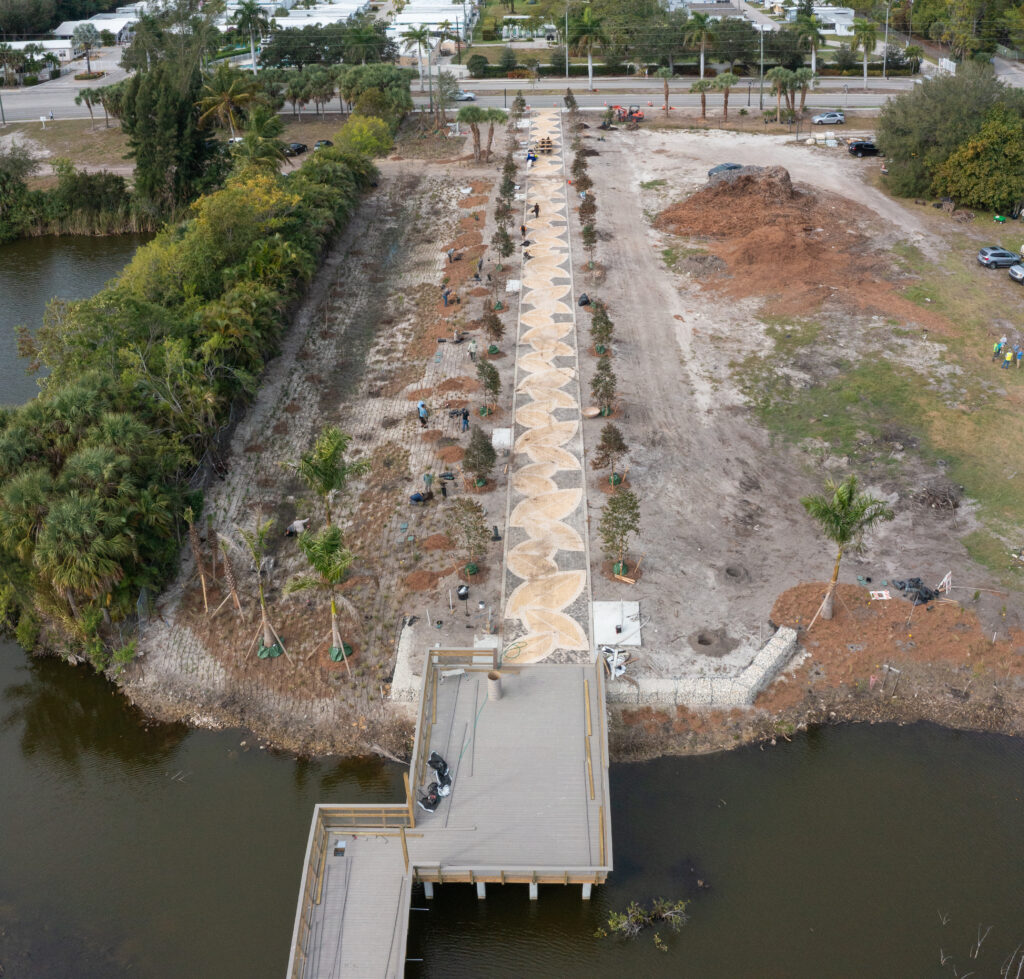 A straight-on aerial shot shows the design of yellow leaves created on the walkway with trees lining each side.