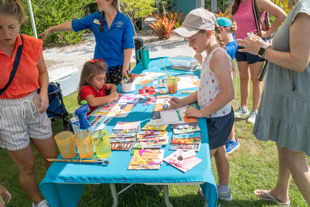 Two children and a few adults gather around a table with activities and props.