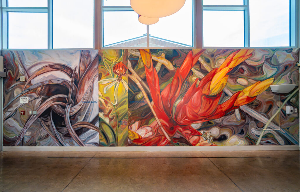 A large mural of three plants spans a wall. On the left there is a macro painting of a tillandsia, next to that an orchid, and on the far right a red bromeliad flower. 